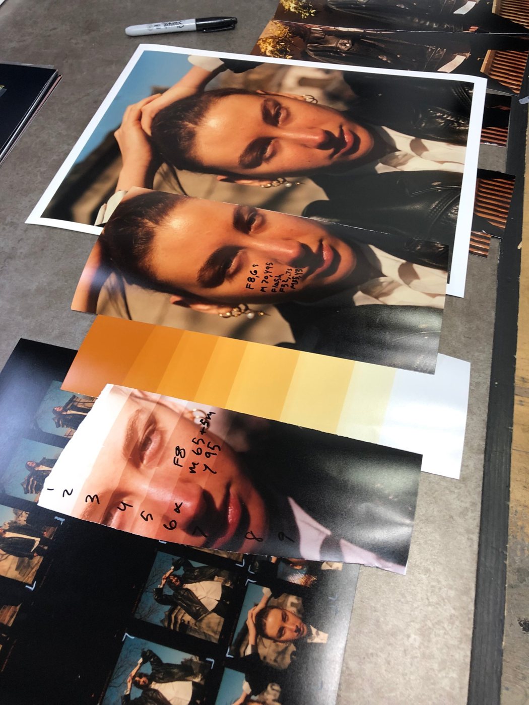 Colour darkroom prints and test strips with handwritten filtration notes, laid out next to a contact sheet